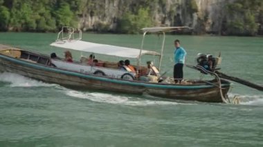 Tracking shot of Thai Captain controlling the DIY wooden motorboat with tourist - Thailand Hopping tour traveling along Railay peninsular, Thailand - 4K Horizontal video