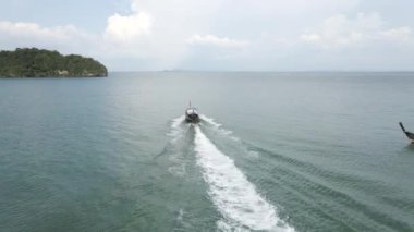 Travel boat with tourists departing from the harbor of Railay Beach, Krabi, Thailand - Following orbiting aerial view - 4K Horizontal video