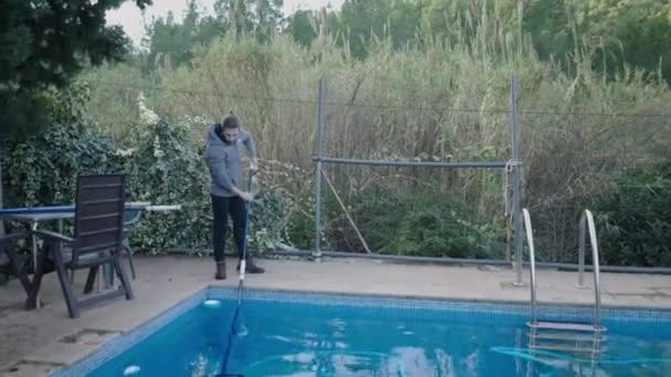 田舎の家でスイミングプールを掃除している若い男 ハウスキーピングのコンセプト 4K水平ビデオ — ストック動画