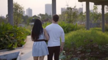 Evli çift Bangkok 'taki Benchakitti parkında yürüyor - çekimlerin arkasında - 4K Yatay Klip