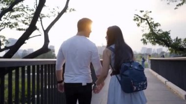 Bangkok 'taki Benchakitti parkında kocasıyla yürüyen sırt çantalı bir kadın - 4K Yatay Klipsi