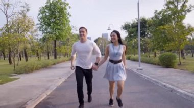 Bangkok 'ta Benchakitti parkında mutlu bir şekilde el ele tutuşan çift - 4K Yatay Klip
