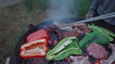 Farklı türde et pişiren tanınmamış bir adam sosisleri çeviriyor - ağır çekim - 4K yatay görüntü