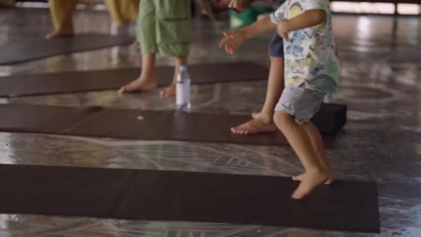 Zugeschnittenes Bild eines intelligenten Kindes, das auf einer Yogamatte in einem spirituellen Zentrum in Thailand tanzt. Mittlere Einstellung, Zeitlupe - 4K Horizontalvideo