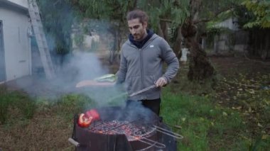 Rahat kıyafetler giyen bir adam ormandaki evinde sebze pişiriyor. 4K yatay video.