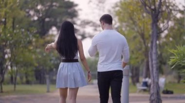 Karı koca, Bangkok 'un yeşil bölgelerinde konuşarak ve gülerek parkta dolaşmayı seviyor - 4K Yatay Klip