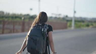 Sırt çantalı genç bir kadın yol kenarında yürüyor - 4K Yatay video