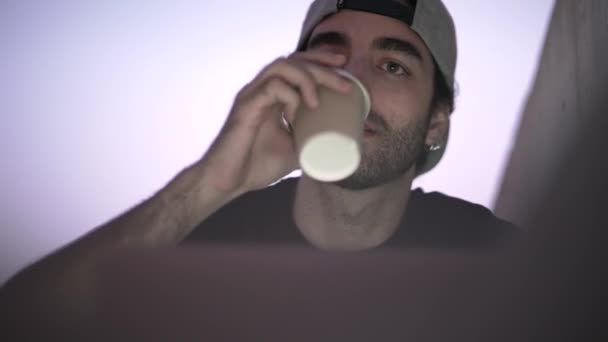 小さなカップからノートパソコンのコーヒーを飲んで目の前の男 画面の光で顔を明るくする 4K水平ビデオ — ストック動画