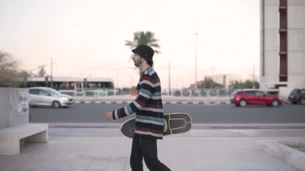 Homem Hipster Carregando Skate Andando Frente Câmera Direita Para Esquerda — Vídeo de Stock