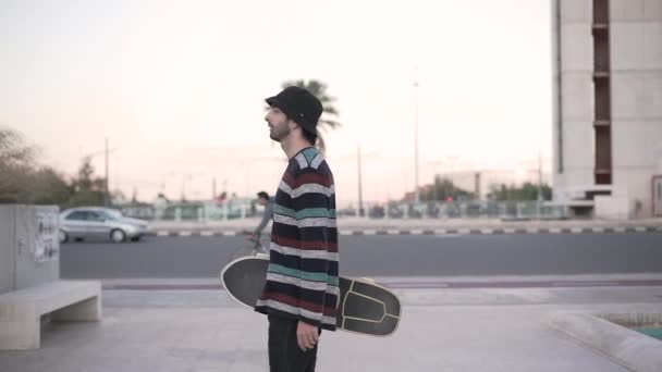 Man Bär Skateboard Och Går Runt Torget Staden Horisontell Video — Stockvideo