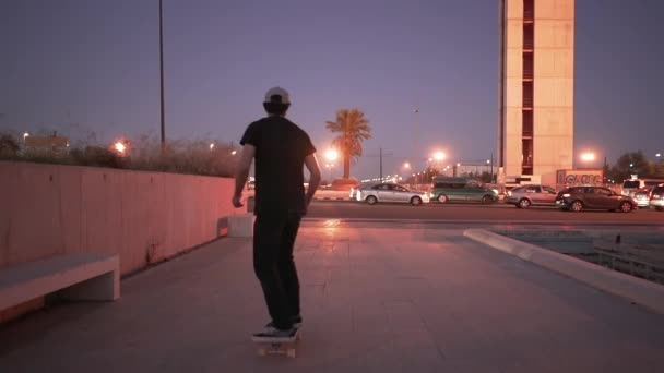 青い時間帯にコンクリート広場の周りでスタイリッシュな男スケート 4K水平ビデオ — ストック動画