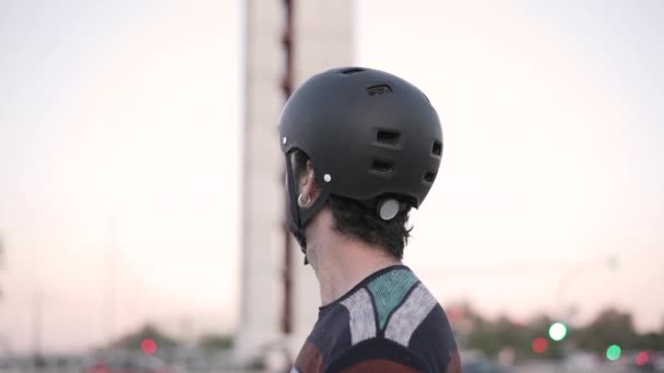 若い男性身に着けているヘルメットのターン周りとカメラを見て スローモーションショット K水平ビデオ — ストック動画