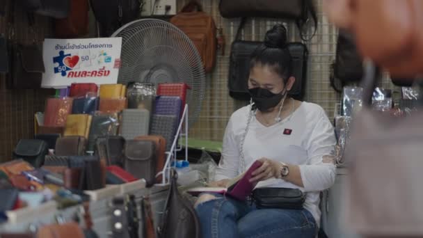 一名亚洲女孩坐在商店看书时戴着黑色面具的静态照片 4K水平视频 — 图库视频影像