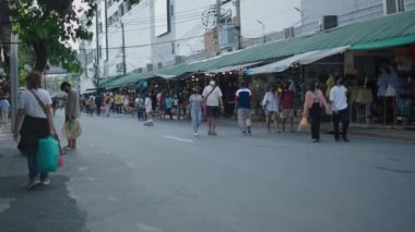Bangkok, Tayland 'daki Chatuchak Market' te insanların yürüdüğü caddenin kenarlarında birden fazla mağaza açık. - 4K Yatay Görüntü