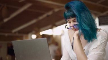 Bilgisayarda çalışan dijital göçebe kadının yakın plan çekimi, başını eline yaslaması ve utangaç gülümsemesi - yavaş çekim - 4K yatay video