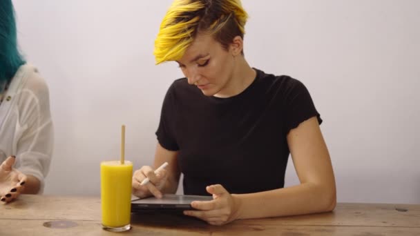 图形设计师与平板电脑和智能手机一起工作 女人坐在木桌边喝橙汁 4K水平视频 — 图库视频影像