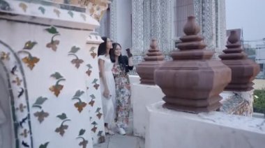 Wat Arun Tapınağı 'na gezintiye çıkmış neşeli kadınlar. Kadınlar etrafta dolanıp birbirleriyle konuşuyorlar - 4K Yatay Video