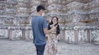 Bangkok 'taki Wat Arun Budist Sarayı' nda iki arkadaş. Erkek kadına akıllı telefonu gösterir ve konuşurlar - 4K yatay video