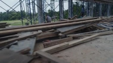 Keresteler ve formlar işçiyle birlikte inşaat sahasının kenarına saçılmış. İzleme Görüntüsü - 4K Yatay Görüntü
