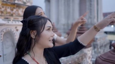 Wat Arun 'daki neşeli kadınlar gökyüzüne bakıyor. Gökyüzü hakkında konuşuyorlar ve gökyüzünü gösteriyorlar - 4K Yatay video