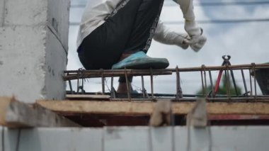 İnşaatta çalışan işçi çelik demiri tamir eden kıskaçlarla. Düşük Açı - 4K Yatay Görüntü