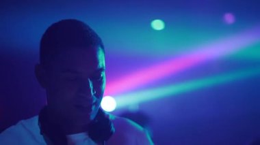 Neşeli DJ kameraya bak ve gülümse. Dans eden, kokteyl içen ve bir partide çalışan bir adam. - 4K Yatay Görüntü