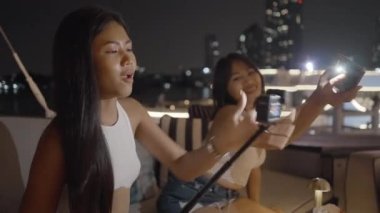 Asyalı kız dışarıda video çekmek için kamerasını kuruyor. Arka planda Bangkok silueti - 4K Yatay Görüntü