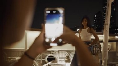 Taylandlı genç bir kadın, kızlar gecesinde barda poz veren arkadaşının fotoğrafını çekiyor - ön manzara - 4K Yatay video