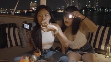 Asyalı youtuber, arkadaşıyla geçirdiği geceyi videoya kaydediyor. Lokantadaki yemeği dene. - 4K Yatay Görüntü