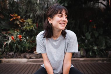 Oturan genç bir kadın gülüyor ve yan tarafa bakıyor - seyahat konsepti