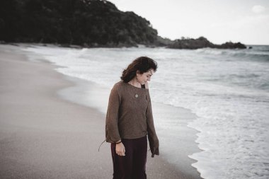 Sahilde gülümseyen genç bir kadın denize bakıyor - doğa konsepti