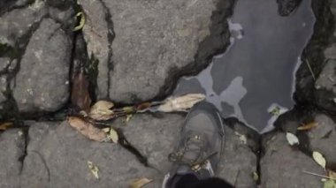 Tanınmayan kişi Kaiate Şelalesi 'ndeki doğal bir şelalenin taşları üzerinde yürüyor - 4K Yatay Video