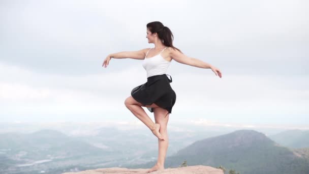 山でヨガのトレーニングセッションを持っている若い女の子 崖の上に立つ女は精神的なヨガを練習しています 横ビデオ — ストック動画
