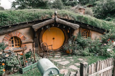 Ormanın yanındaki dağda gömülü meraklı ve güzel bir ev yuvarlak ahşap kapılı ve pencereli eski bir rockçı, Mount Maunganui, Yeni Zelanda - seyahat konsepti