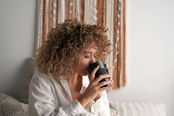 Beyaz tişörtlü, kıvırcık saçlı, sakin bir kadın. Sabahları rahat bir yatak odasında kahvaltı yaparken gözleri kapalı taze kahve içiyor.