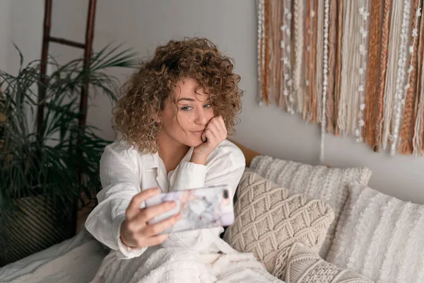 Mujer Joven Con Pelo Rizado Ropa Casual Sentada Cama Mirando —  Fotos de Stock