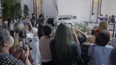 Asyalı kadınlar Bangkok, Tayland 'daki alışveriş merkezinde yakışıklı kişilerin fotoğraflarını çekiyor. Sağa çevir, yavaş çekim - 4K Yatay video