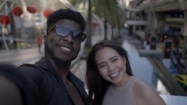 Mutlu ırklar arası çift fotoğraf makinesi için selfie modunda poz veriyor. Çiftler birbirleriyle ahmakça oynuyorlar - 4K Yatay Video