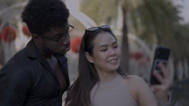 Fotoğraf çekmek için akıllı telefon kullanan çok yönlü çiftin yakın çekimleri. Aptal erkek arkadaş kızı güldürüyor - 4K Yatay video