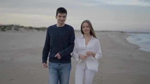 友人のカップル笑顔とビーチで歩く 海岸に当たる海の波の眺め 4K水平ビデオ — ストック動画