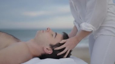 Genç İspanyol erkek baş masajı yaptırırken rahatlıyor, masözün manzarası aşağı bakıyor - 4K yatay görüntü