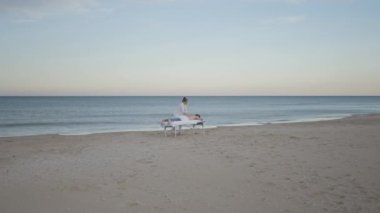 Profesyonel masaj terapistinin müşteriye deniz kıyısında şifa tedavisi uygulaması - 4K Yatay Video