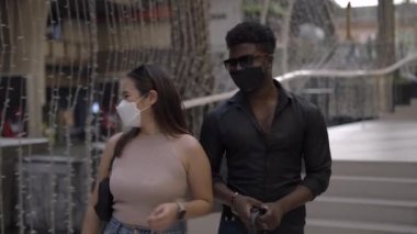 Alışveriş merkezinde maskeli çok ırklı bir çift dolaşıyor - yakın çekim - 4K Yatay video