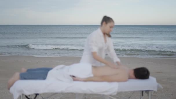Mężczyzna Leży Stole Masażu Plaży Nieskupiony Morzem Ruch Tle Horizontal — Wideo stockowe