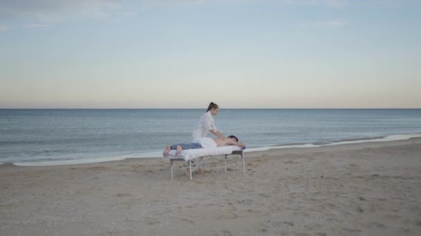 Junger Kaukasier Bekommt Professionelle Rückentherapie Strand Zeitlupenaufnahme Horizontalvideo — Stockvideo