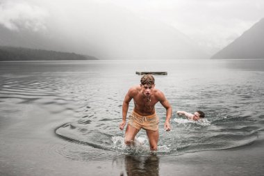 Kafkas çocuk sudan yorgun bir şekilde çıkıyor. Ağzı açık halde tahta platformda yüzdükten sonra çok bulutlu ve sisli bir günde Nelson Gölleri, Yeni Zelanda 'da seyahat ediyor.