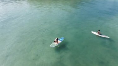 Kürek tahtasında amuda kalkan adam ve yoga pozu veren kadın - hava görüntüsü - 4K yatay video