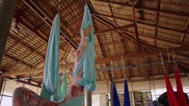 Büyük yoga stüdyosundaki kırmızı hamakta oturan tanınmayan Latin kadın bacakları - 4K yatay video