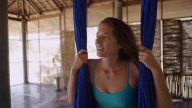 Hava yogası sırasında kelebek pozu veren rahat erkek. Adam mor hamakta asılı - yatay 4K video