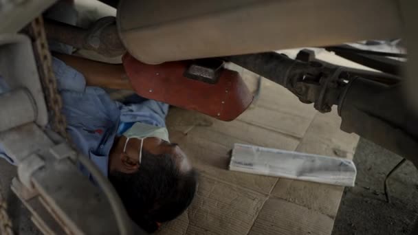 Asiatisk Mekaniker Reparera Bil Underifrån Med Hjälp Blåslampa Och Skyddande — Stockvideo